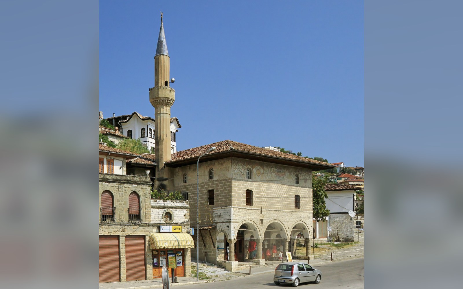 An Ottoman mosque with a stone minaret at the foot of a hillside of stacked houses