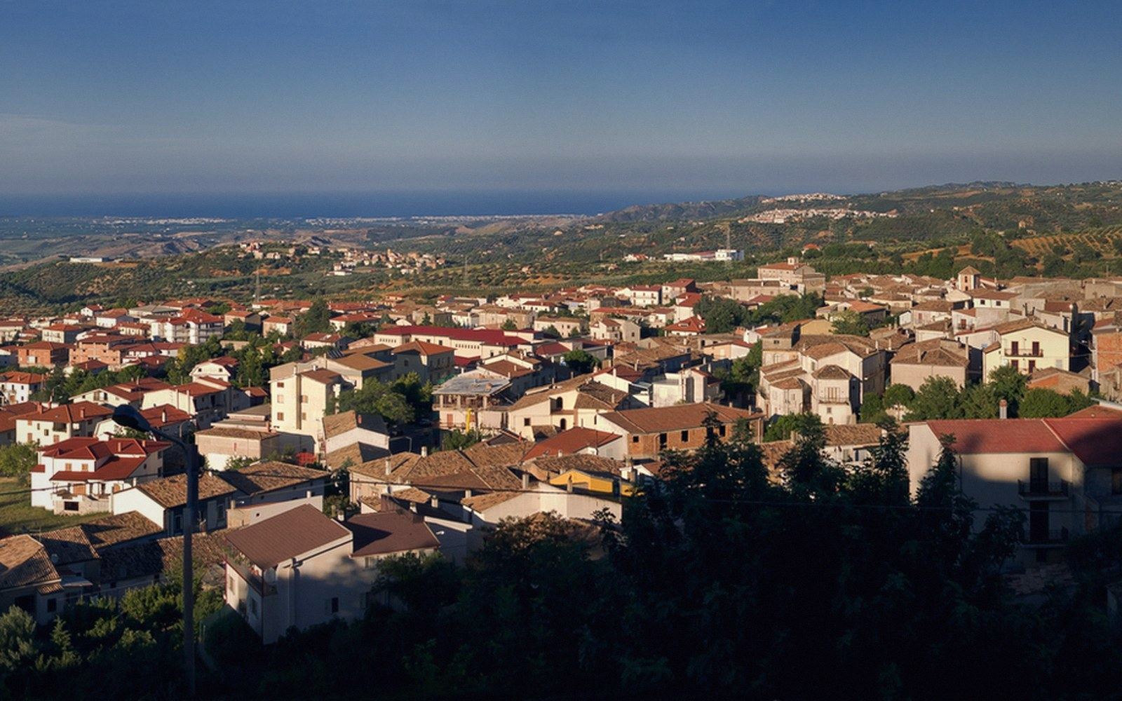 Tiled roofs of a Calabrian hill town with the coastal plain and sea beyond